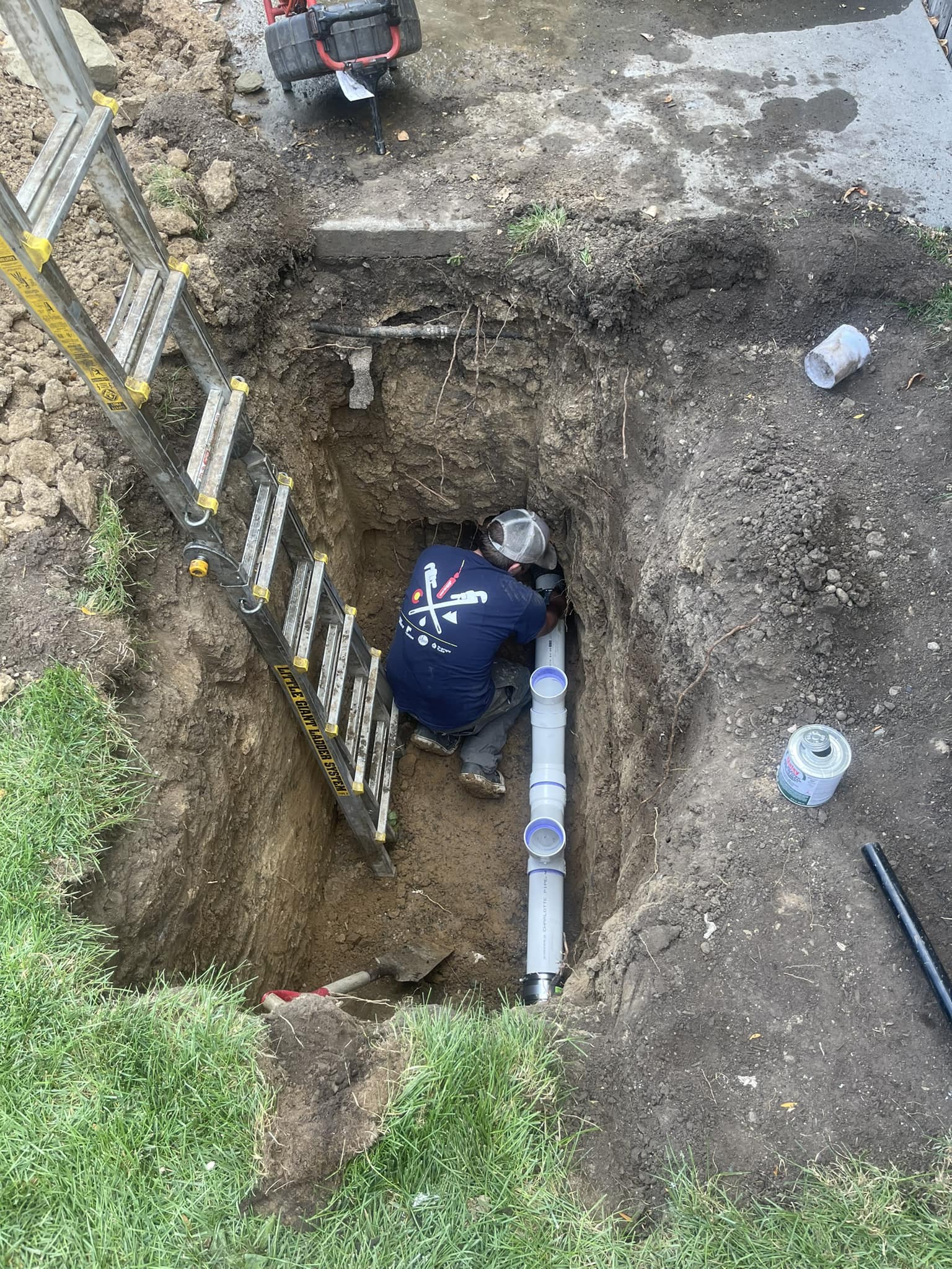 Sewer line repair — worker in trench with PVC pipe